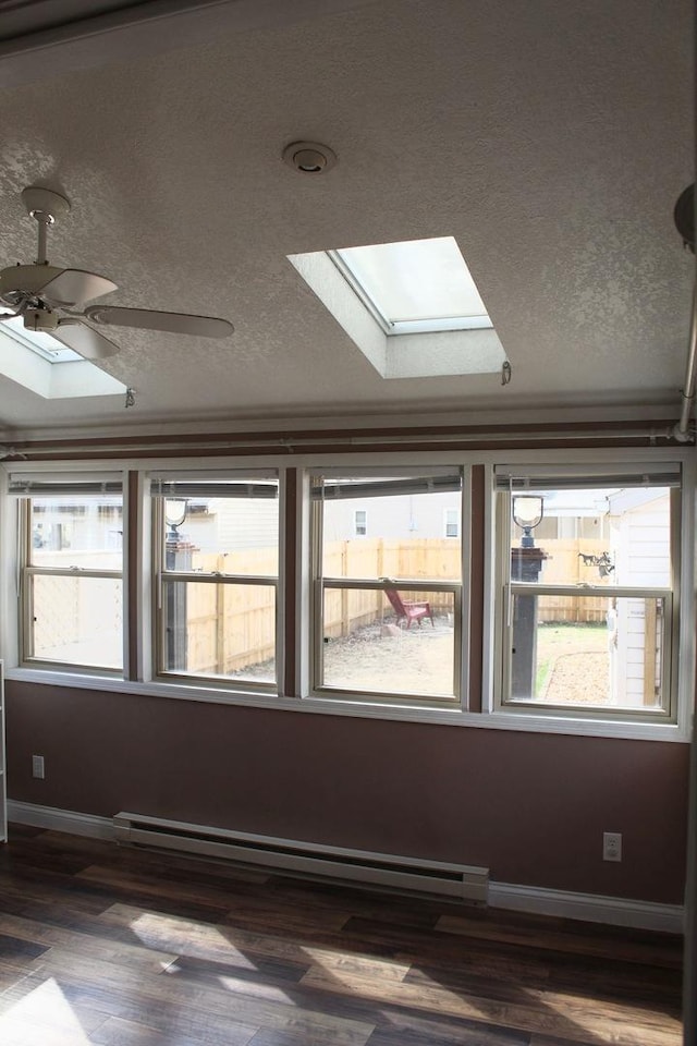 empty room featuring a skylight, a healthy amount of sunlight, and baseboard heating