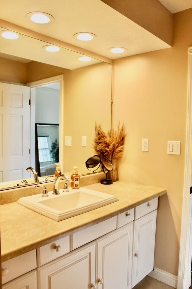 bathroom featuring baseboards, recessed lighting, and vanity