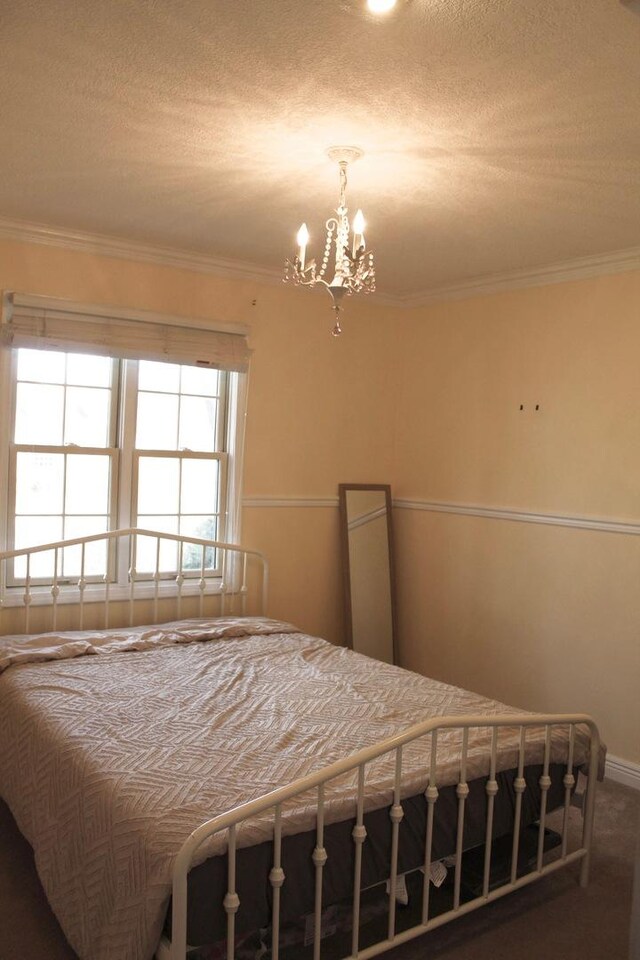 bedroom with carpet flooring, a textured ceiling, crown molding, and a notable chandelier