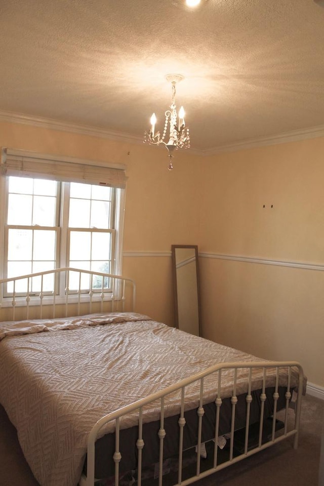 bedroom with carpet flooring, a notable chandelier, ornamental molding, and a textured ceiling
