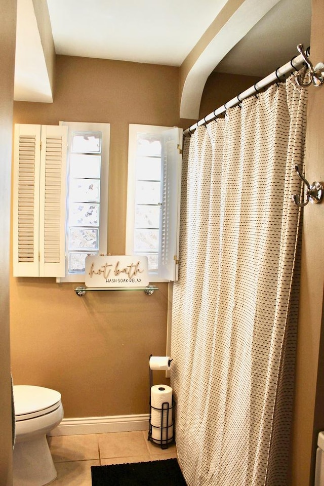 bathroom featuring a shower with curtain, tile patterned floors, toilet, and baseboards