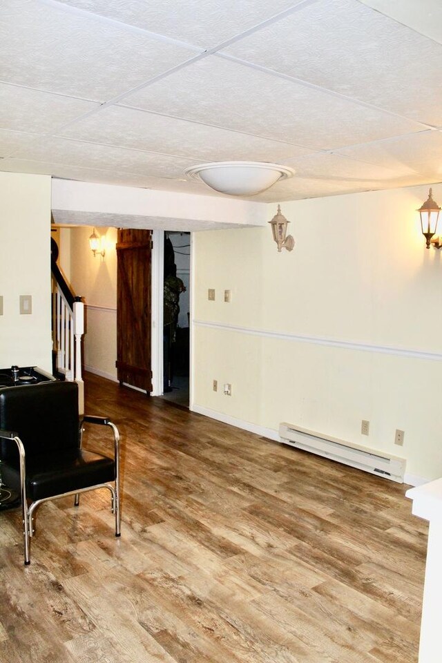 living area featuring a baseboard radiator, wood finished floors, and stairs
