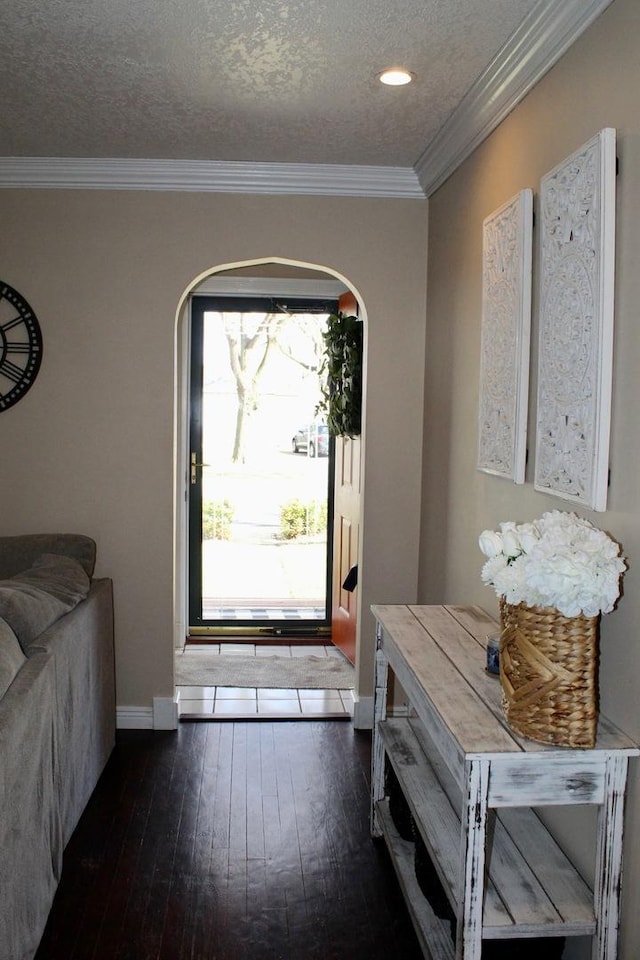 entrance foyer with a textured ceiling, baseboards, ornamental molding, wood finished floors, and arched walkways