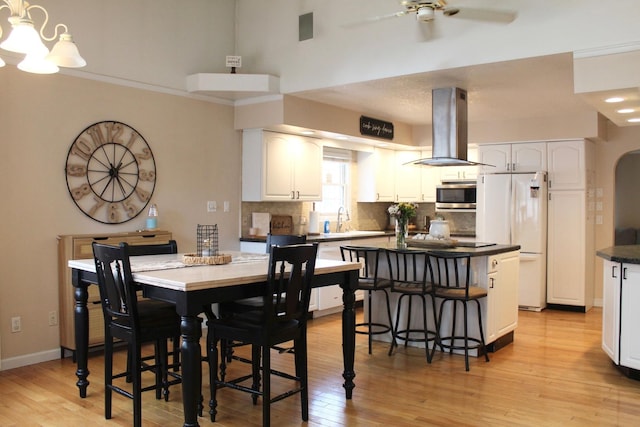 dining area featuring ceiling fan with notable chandelier, baseboards, and light wood-type flooring