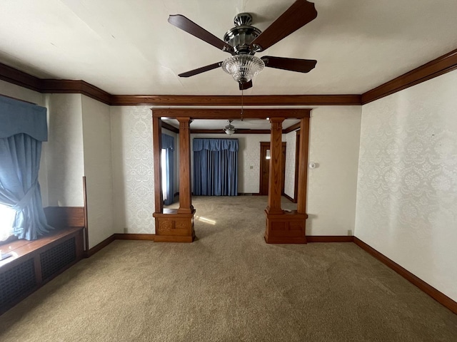 carpeted empty room with a ceiling fan, ornamental molding, baseboards, and ornate columns