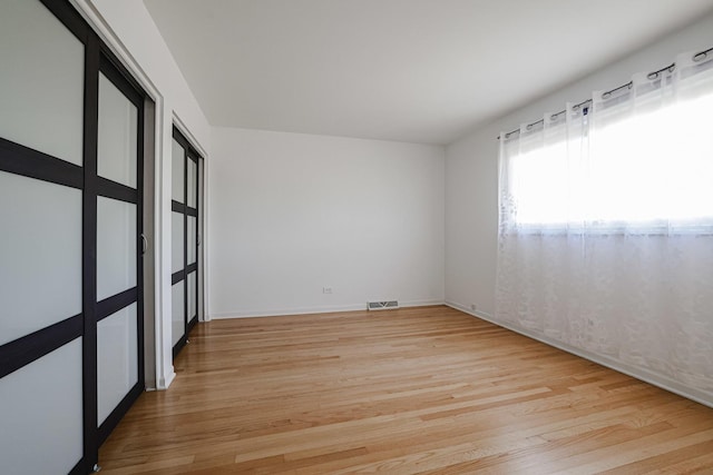unfurnished room featuring baseboards, visible vents, and light wood-style flooring