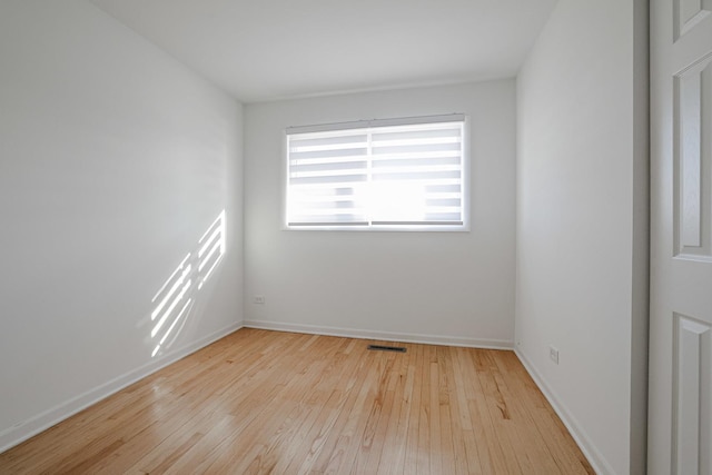 spare room featuring hardwood / wood-style floors, baseboards, and visible vents