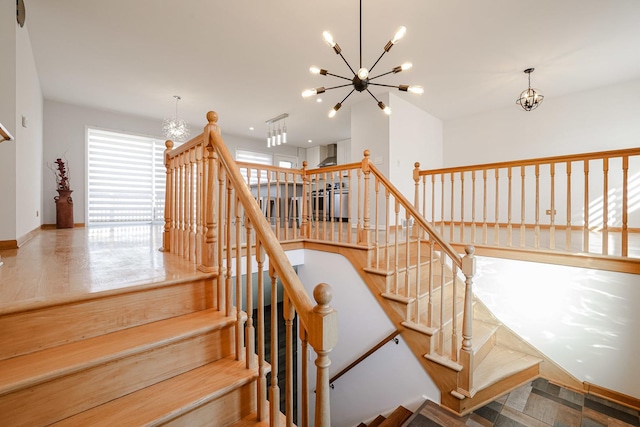 staircase with a notable chandelier and baseboards