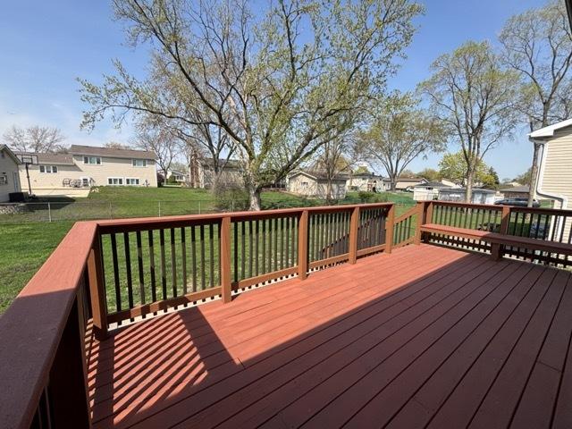 wooden terrace with a lawn, fence, and a residential view