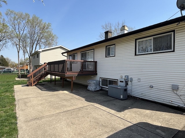 back of property with stairway, a deck, a patio area, and a chimney