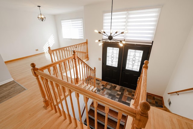entryway with visible vents, wood finished floors, a chandelier, and baseboards