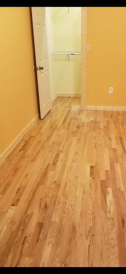 unfurnished bedroom with a closet, baseboards, and light wood finished floors