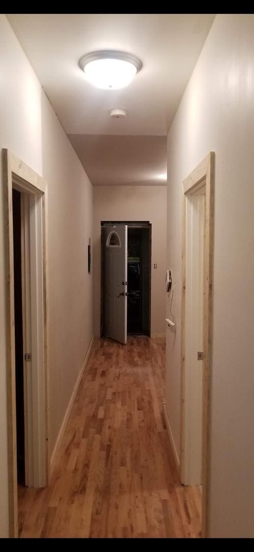 corridor featuring baseboards and light wood-style floors
