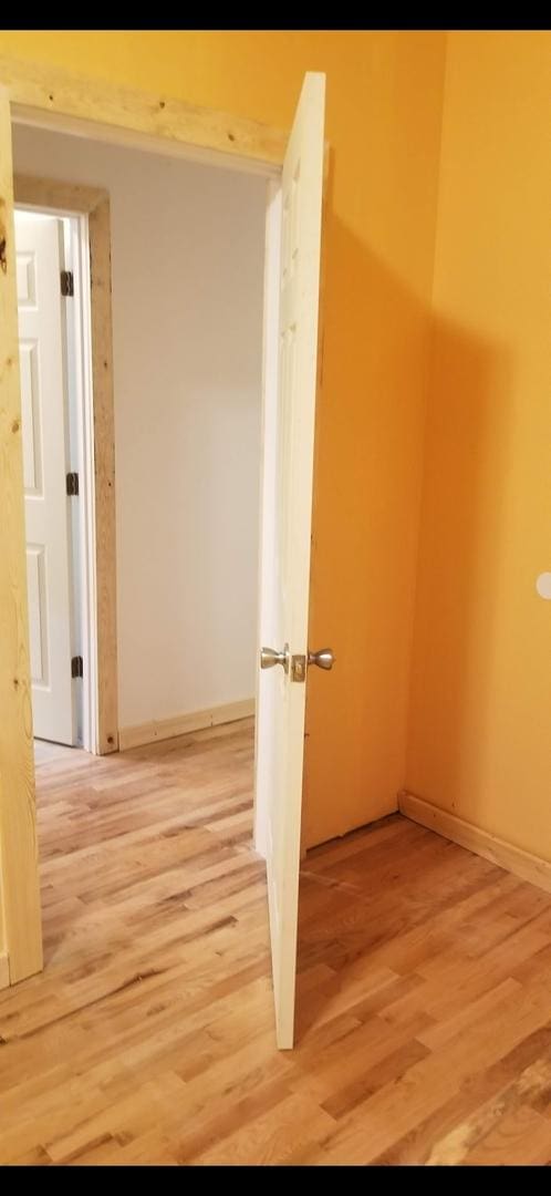 hall with light wood-style flooring and baseboards