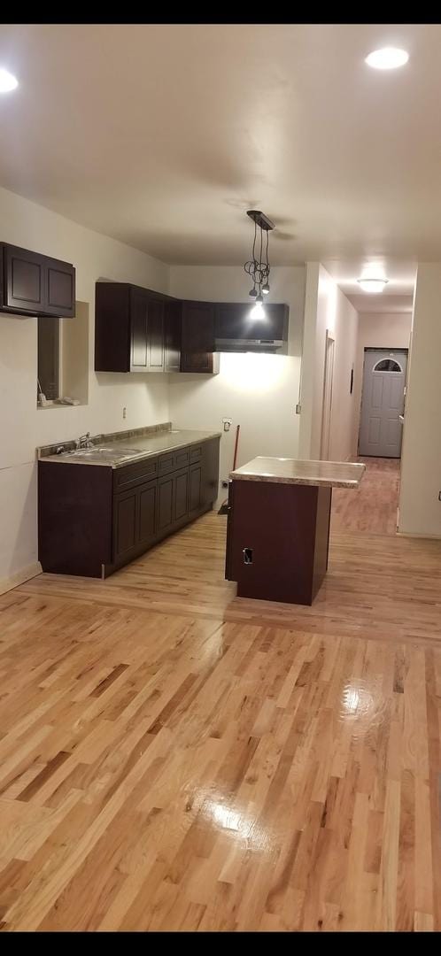 kitchen with a sink, light wood-style flooring, decorative light fixtures, and a kitchen island