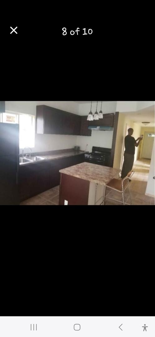 kitchen featuring stainless steel refrigerator, a sink, under cabinet range hood, and black gas stove