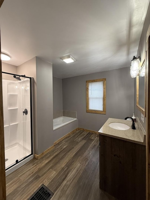 full bath featuring a bath, wood finished floors, a stall shower, and vanity