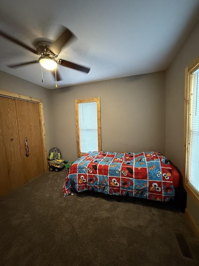 carpeted bedroom featuring a ceiling fan and visible vents