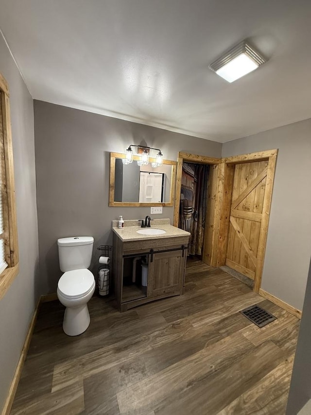 bathroom featuring toilet, visible vents, wood finished floors, and baseboards