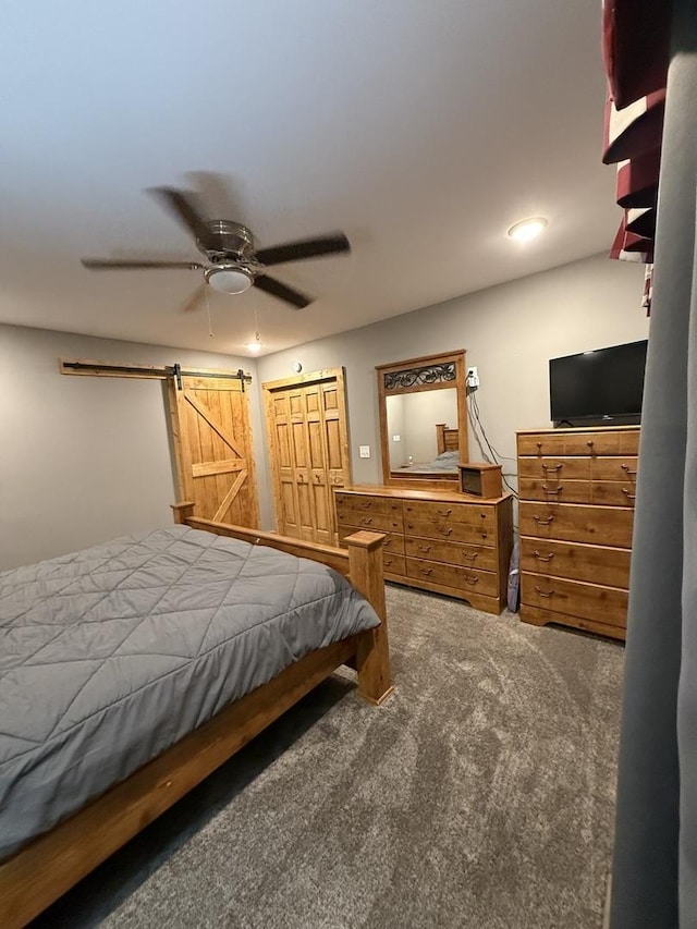 bedroom featuring a ceiling fan, carpet, and a barn door