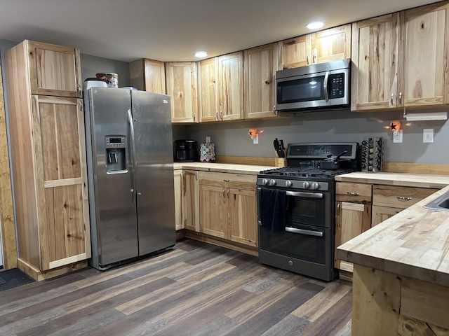 kitchen with dark wood-style flooring, butcher block counters, light brown cabinetry, and appliances with stainless steel finishes