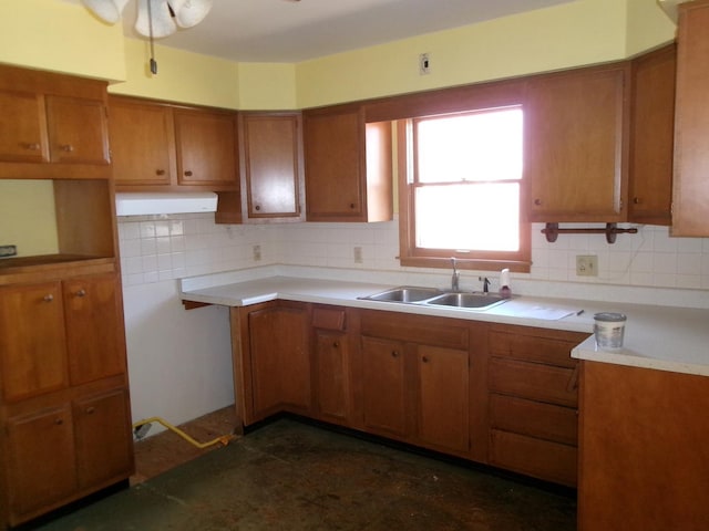 kitchen with light countertops, a sink, tasteful backsplash, brown cabinets, and ceiling fan