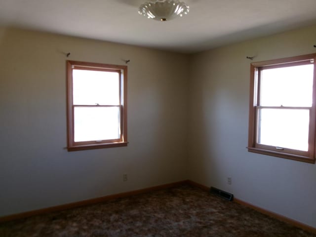 spare room with baseboards, visible vents, and a healthy amount of sunlight