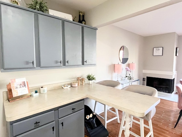 650 Cress Creek Ln, Crystal Lake, IL 60014 - kitchen with gray cabinetry, light wood-style flooring, light countertops, a fireplace, and a peninsula
