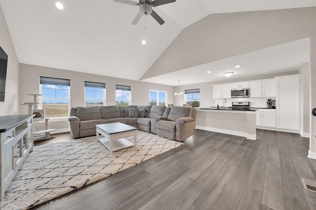 living area featuring high vaulted ceiling, a wealth of natural light, wood finished floors, and a ceiling fan