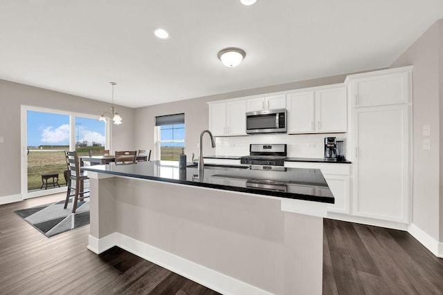 kitchen featuring tasteful backsplash, stainless steel appliances, a sink, dark countertops, and dark wood-style floors