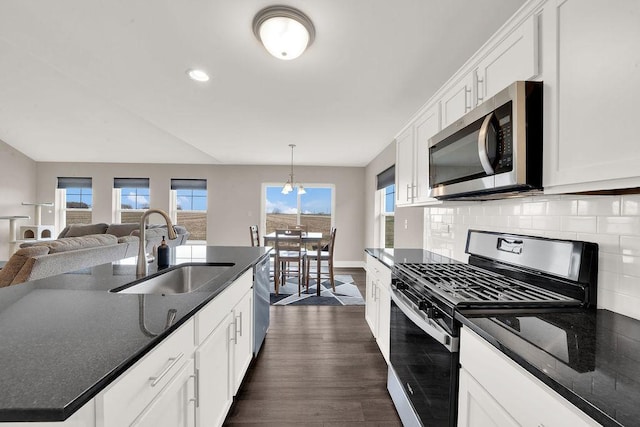 kitchen with white cabinetry, dark wood-style flooring, backsplash, a sink, and appliances with stainless steel finishes
