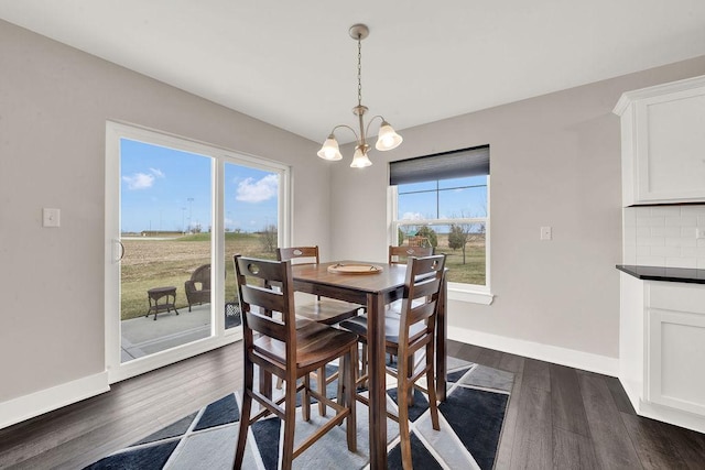 dining space featuring dark wood-style floors, baseboards, and an inviting chandelier