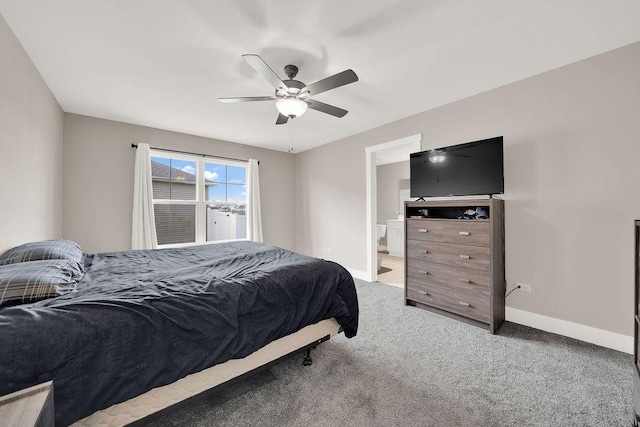 bedroom featuring light carpet, baseboards, ensuite bathroom, and a ceiling fan