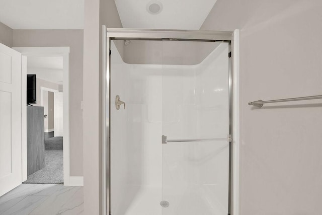 bathroom featuring marble finish floor, baseboards, and a stall shower