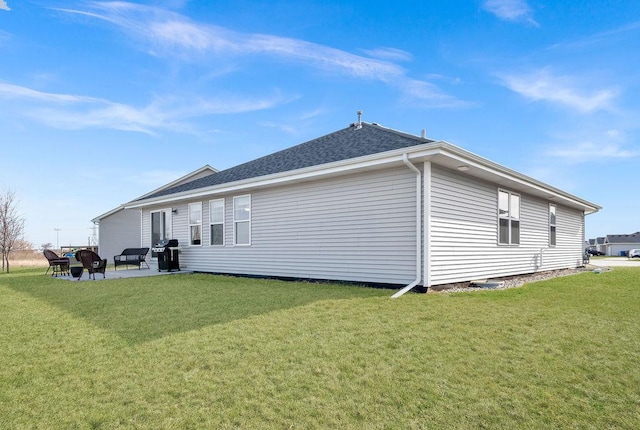 rear view of property featuring a lawn, a patio area, and roof with shingles