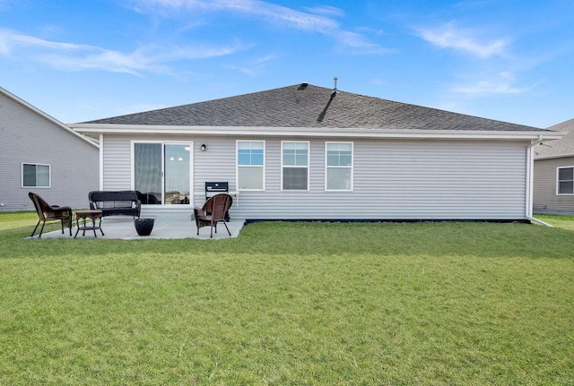 back of house featuring a lawn, a shingled roof, and a patio