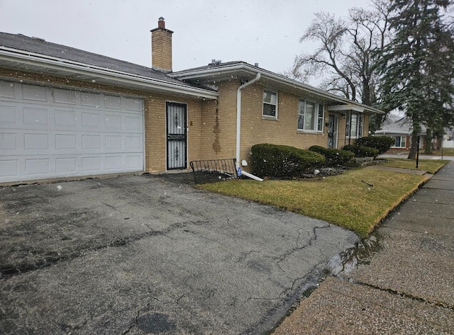 view of front of house with an attached garage, brick siding, and a chimney