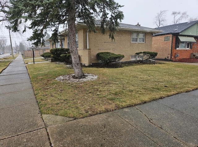 view of side of home featuring a lawn and brick siding