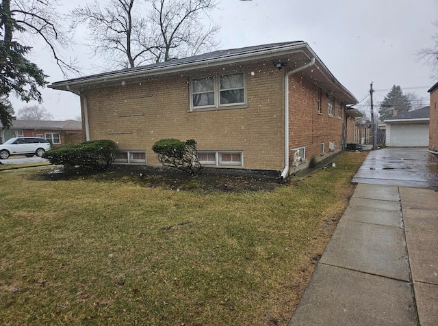 view of side of property featuring a garage, an outdoor structure, brick siding, and a yard