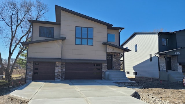 contemporary house with stone siding, driveway, and an attached garage