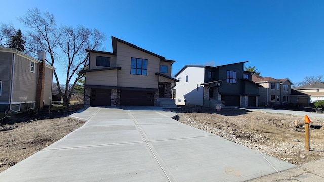 contemporary house with stone siding, a residential view, concrete driveway, and an attached garage