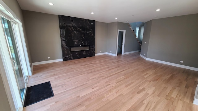 unfurnished living room with visible vents, recessed lighting, light wood-type flooring, and stairway