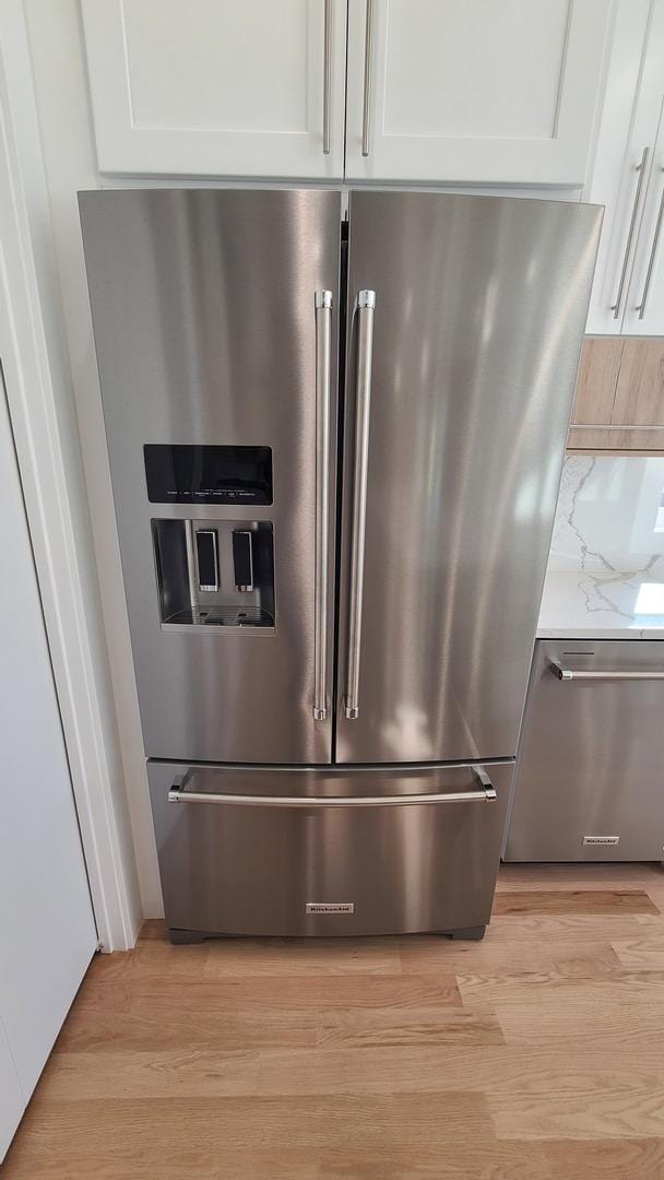room details with white cabinetry, stainless steel appliances, and light wood-type flooring