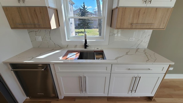 kitchen with white cabinetry, light stone countertops, tasteful backsplash, and a sink