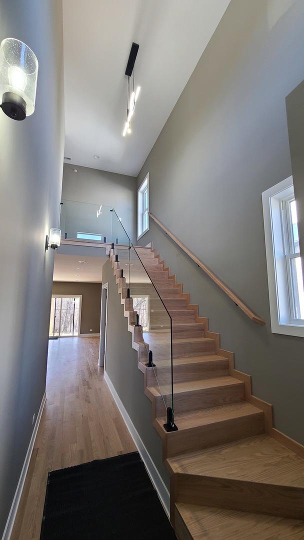 stairway featuring baseboards, a high ceiling, and wood finished floors