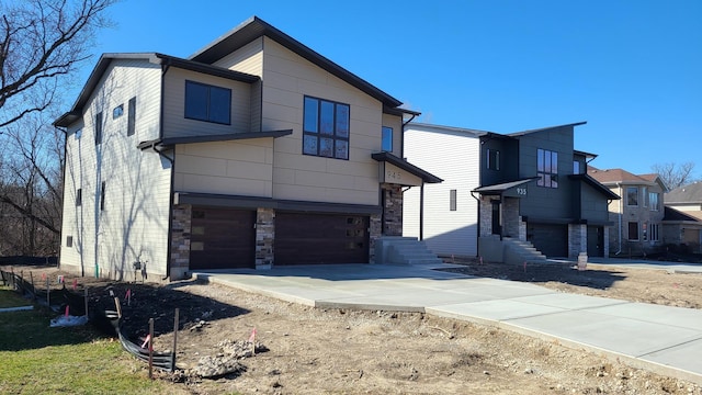 contemporary home featuring stone siding, driveway, and a garage