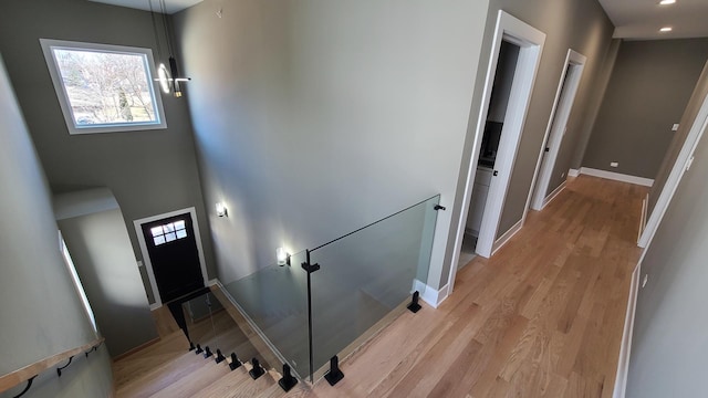 staircase featuring baseboards, wood finished floors, and recessed lighting
