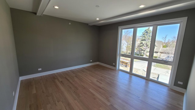 spare room featuring baseboards, beamed ceiling, wood finished floors, and recessed lighting