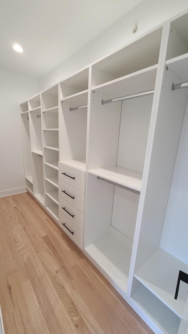 walk in closet with light wood-style flooring