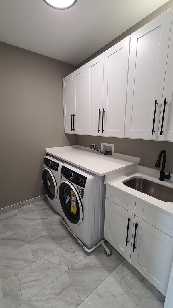 clothes washing area with marble finish floor, washing machine and dryer, cabinet space, and a sink